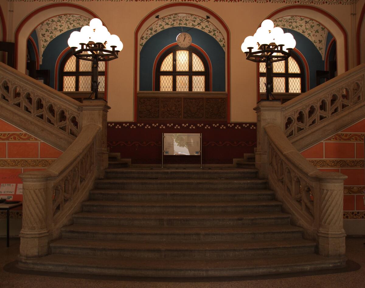 Historisches Treppenhaus mit zwei geschwungenen Treppen und Kronleuchtern