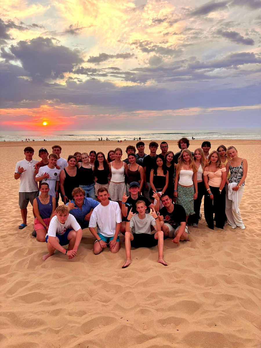 Gruppenbild des Oberstufenkurses Surfen am Strand bei Sonnenuntergang